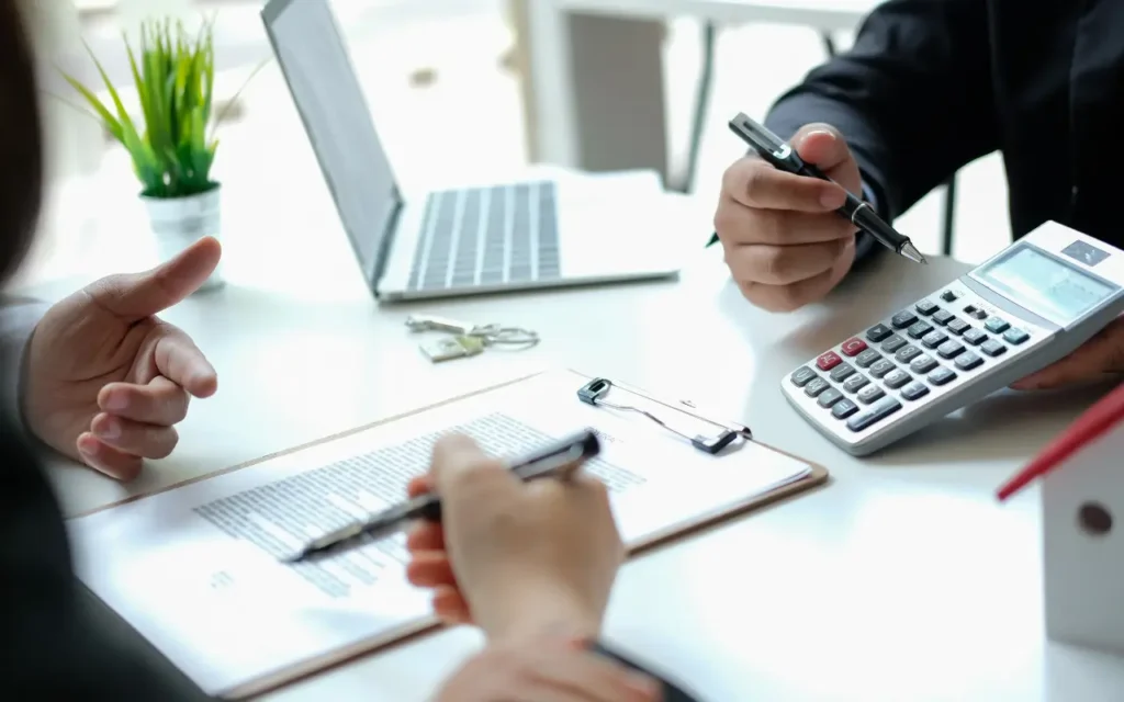 duas pessoas apontando para um contrato e uma calculadora, fazendo referência à negociação de serviços com seguro de responsabilidade social