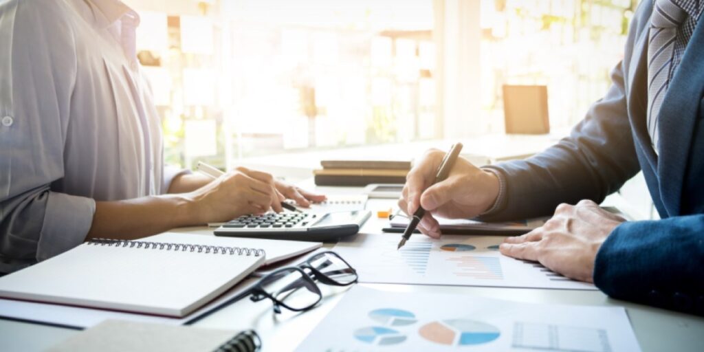 duas pessoas analisando números e fazendo anotações