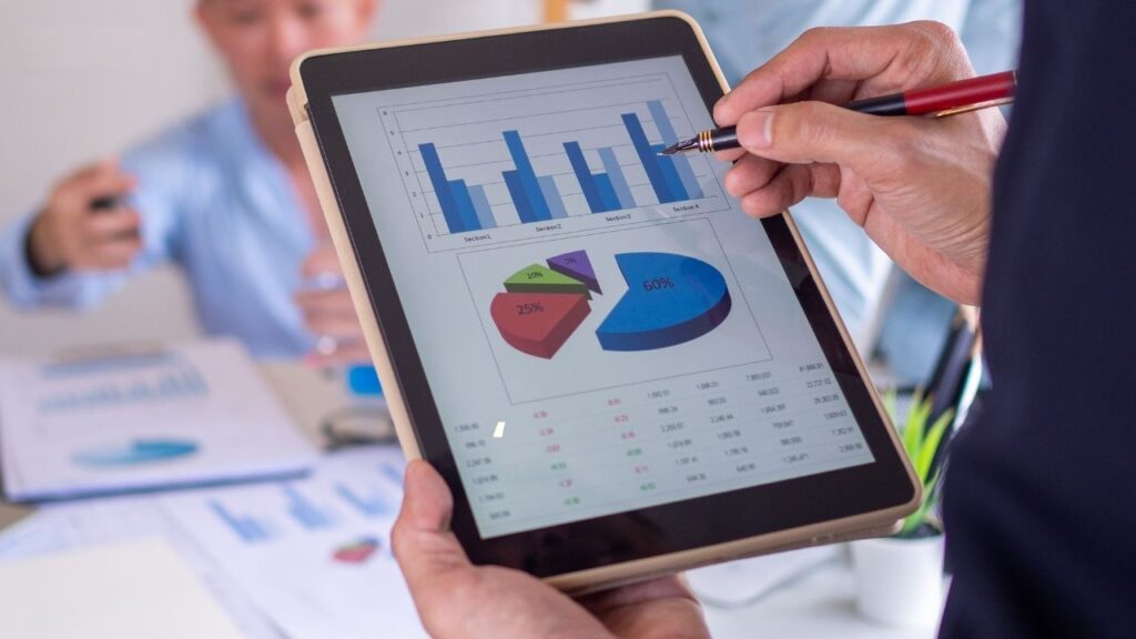 Pessoa analisando gráficos em um tablet, representando análise de dados ou desempenho empresarial.